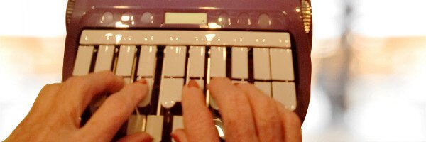 Hands typing on a stenotype machine.